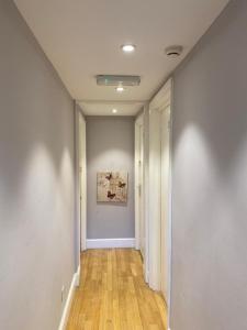 a hallway with white walls and wooden floors and a painting at Flat w/ terrace in Notting Hill in London