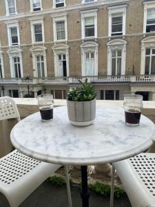 a table with two glasses and a potted plant on it at Flat w/ terrace in Notting Hill in London