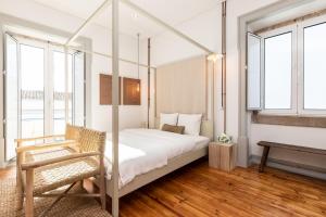 een slaapkamer met een hemelbed en een stoel bij Amália Boutique Suites & Studios - by @ rita´s place in Faro