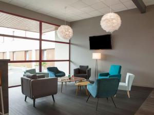 a waiting room with chairs and a table and a tv at The Originals City, Plume Hôtel, Bressuire (Inter-Hotel) in Bressuire