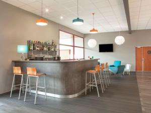 a bar in a room with chairs and a counter at The Originals City, Plume Hôtel, Bressuire (Inter-Hotel) in Bressuire