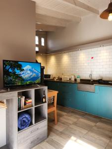 a kitchen with blue cabinets and a flat screen tv at La Casita in Junín de los Andes