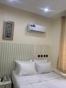 a hotel room with a bed with a air conditioner on the wall at Bott Extended Stay in Abuja