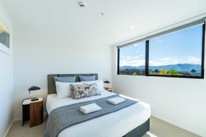 ein Schlafzimmer mit einem Bett mit einem großen Fenster in der Unterkunft Majestic Mountain-View Retreat in Wanaka