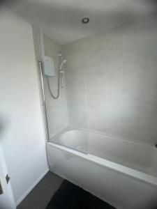 a white bathroom with a tub and a shower at The Coral Guest House 1 Fratton Park Portsmouth in Portsmouth