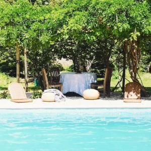 una mesa y sillas junto a una piscina en 1700's Country House with large Private Pool & Gardens en Villeneuve-dʼAveyron