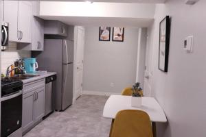 een keuken met witte kasten en een tafel met stoelen bij Deluxe 2 bedroom suite with*Netflix/Cable/Prime in Edmonton