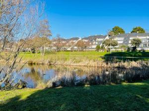 un estanque en un parque con casas al fondo en ARZON TERRASSE DE KERJOUANNO, en Arzon