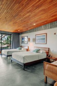 two beds in a bedroom with a wooden ceiling at Puro Surf Hotel & Performance Academy in El Zonte