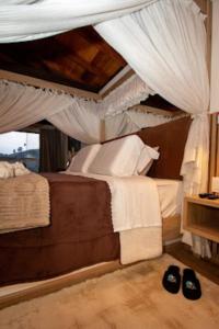 a bedroom with a canopy bed with two pairs of shoes at Pousada Colina das Andorinhas in Gonçalves