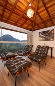 Habitación con sillas de cuero y ventana grande. en Pousada Colina das Andorinhas en Gonçalves