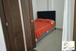 una piccola camera con un letto con una coperta rossa di Hostal Sinaí a Mocoa