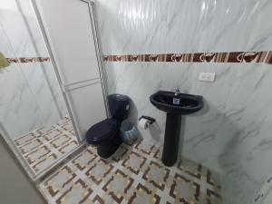 a bathroom with a toilet and a black sink at Hostal Sinaí in Mocoa