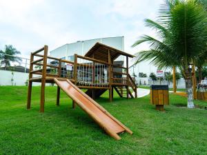 un parque infantil de madera con un tobogán en el césped en Hotel BHS en Linhares