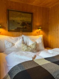 a bed with white sheets and pillows in a bedroom at Rostad Retro Rorbuer in Reine