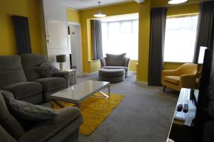Huge 9 Bed Property Sleeps 17, Near NEC, City Centre, HS2 في برمنغهام: غرفة معيشة مع أريكة وكراسي وطاولة