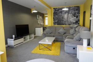 Huge 9 Bed Property Sleeps 17, Near NEC, City Centre, HS2 في برمنغهام: غرفة معيشة مع أريكة وتلفزيون