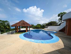 a swimming pool with a gazebo next to a building at Cabinas Copal en Copal KiteBeach in Playa Copel