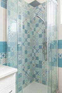 ein Bad mit einer Dusche mit blauen und weißen Fliesen in der Unterkunft Casa Vacanze Nonna Rosaria al centro di Ascea Marina in Ascea