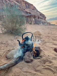 a fire with a pot on top of it in the desert at Lma Luxury Camp in Wadi Rum