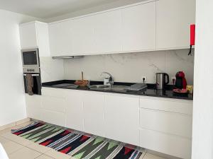 a kitchen with white cabinets and a sink at Mine House in Calheta