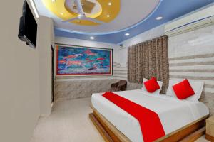 a bedroom with a bed with red pillows and a tv at POP Hotel Dk Guest House in Ahmedabad