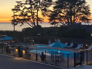 a pool with chairs and umbrellas at sunset at Castle Inn in Cambria