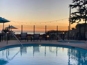 a swimming pool with chairs and a sunset in the background at Castle Inn in Cambria