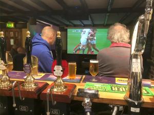 a group of people sitting at a bar watching a soccer game at The Bickford Arms Inn in Holsworthy