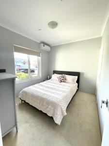 a bedroom with a bed with a white comforter and a window at Ocean Reef Retreat in Perth