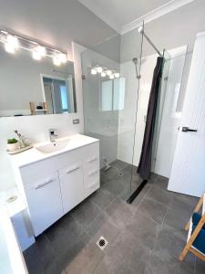 uma casa de banho com um lavatório branco e um chuveiro em Ocean Reef Retreat em Perth