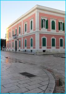 Edificio grande de color rosa con puertas y ventanas verdes en Palazzo De Giorgi B&B, en Lecce