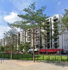 a tree in a park in front of a building at Luxury en-suite room Olympic Village in shared apartment in London