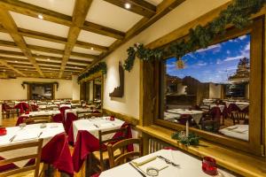 ein Restaurant mit Tischen und Stühlen und einem großen Fenster in der Unterkunft Hotel Sauze in Sauze dʼOulx