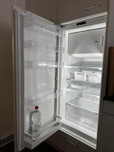 an empty refrigerator with a bottle of water in it at Gemütliche möbilierte Wohnung in Winterthur in Winterthur