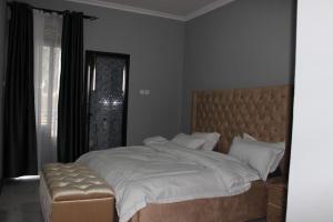 a bedroom with a large bed with a tufted headboard and a window at MHP Apartments in Munyonyo