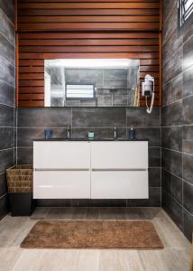 ein Badezimmer mit einem weißen Waschbecken und einem Spiegel in der Unterkunft HABITATION SUNSHINE - PISCINES PRIVÉES + SAUNA COMMUN in Saint-François