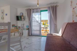 ein Wohnzimmer mit einem Sofa, einem Tisch und einem Fenster in der Unterkunft Dunas of Love in Caleta de Fuste