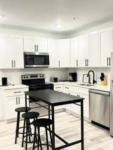 a kitchen with white cabinets and a black table and stools at Extravagant 3 Bedroom Near art Museum in Philadelphia