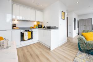 a kitchen and living room with white cabinets at Bright Stylish Studio Apartment in Old Trafford in Manchester