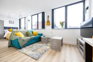 een woonkamer met een blauwe bank en een gitaar bij Bright Stylish Studio Apartment in Old Trafford in Manchester