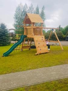 a wooden playground with a slide and a swing at Gintagnė 