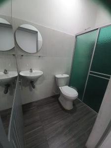 ein Badezimmer mit einem WC, einem Waschbecken und einem Spiegel in der Unterkunft Hotel Oiti 