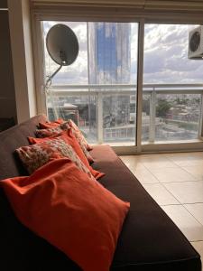Sofá con almohadas en una habitación con ventana grande en Departamento Minimalista Cordoba en Córdoba