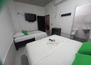 a hotel room with two beds and a tv at Hotel Oiti 