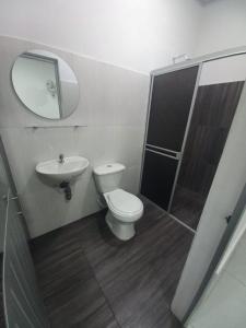 a bathroom with a toilet and a sink and a mirror at Hotel Oiti 