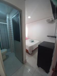 Habitación pequeña con cama y puerta al baño en Hotel Oiti, 