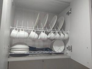 une cuisine avec des assiettes et de la vaisselle blanches sur une étagère dans l'établissement Apartamento acogedor confortable y céntrico para 2, à Armenia