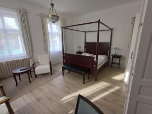 ハイドゥーナーナーシュにあるTornácos Vendégházのベッドルーム(天蓋付きベッド1台、椅子付)