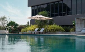 リーブルヴィルにあるRadisson Blu Okoume Palace Hotel, Librevilleの建物の隣にプール(椅子2脚、パラソル付)があります。